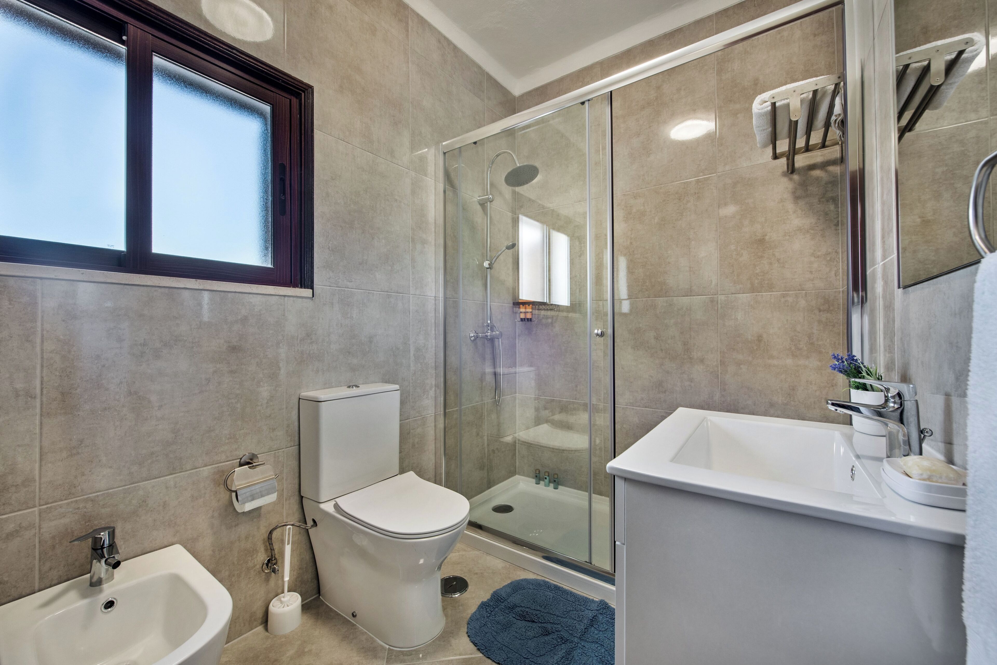 A modern bathroom with a glass-enclosed shower, a white sink, and a toilet.