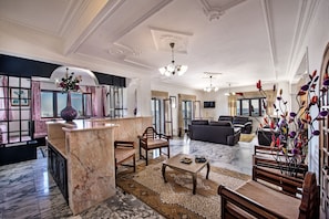 Uma sala ampla com piso de mármore, uma mesa de centro, um sofá e um arranjo decorativo de plantas.