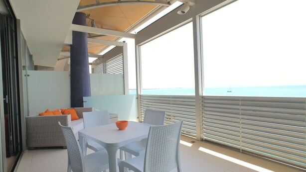 A balcony with a table and chairs, a view of the sea, and a glass partition. - Bilocale Marina (Gallipoli)