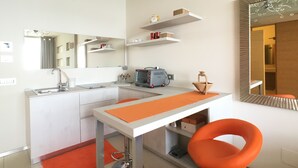 A modern kitchen with a sink, countertop, and a coffee machine. There are shelves above the counter and a mirror on the wall. - Bilocale Marina (Gallipoli)