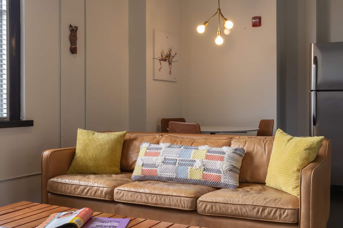 A cozy living room with a leather sofa, wooden coffee table, and a hanging light fixture.