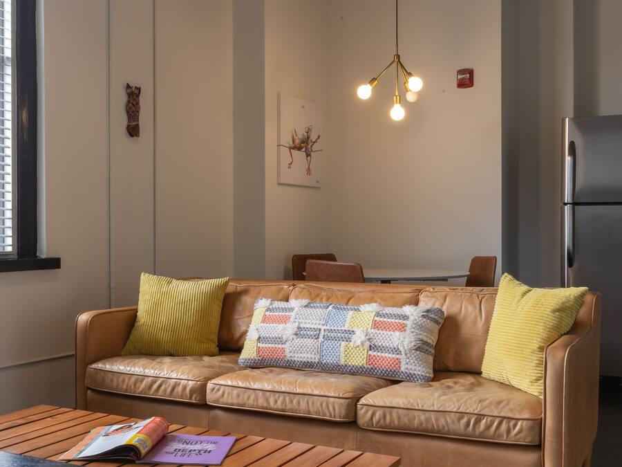 A cozy living room with a leather sofa, wooden coffee table, and a hanging light fixture.