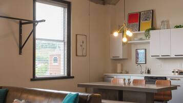 A modern kitchen with white cabinets, a central island, and a hanging light fixture.