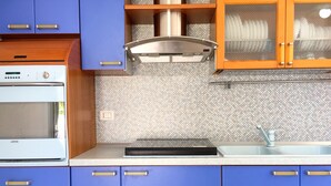A kitchen with blue cabinets, a white oven, a stainless steel range hood, and a sink with a modern faucet.