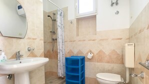 A bathroom with a sink, toilet, shower, and a blue storage unit.