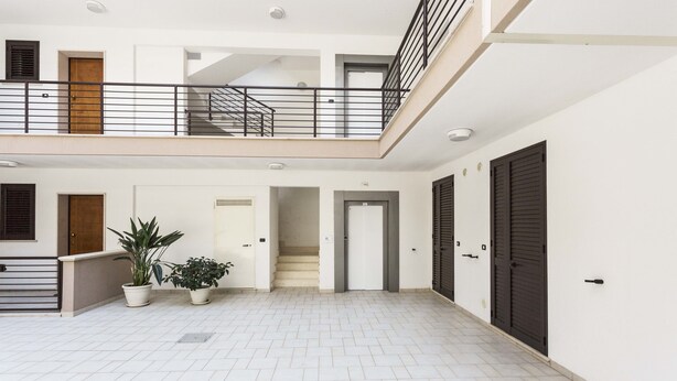 A spacious indoor area with a tiled floor, a staircase, and a balcony.