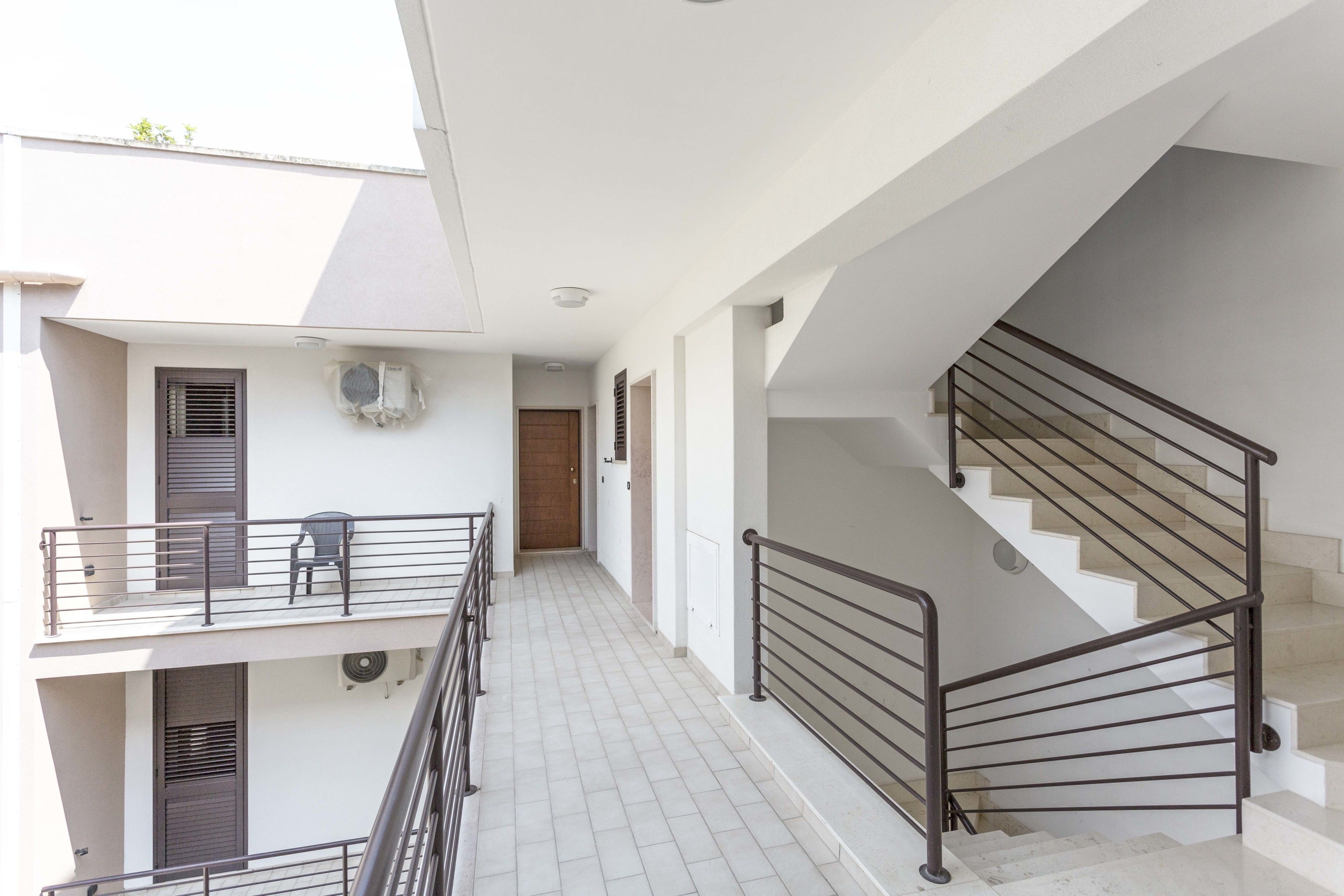 A multi-level residential building with a staircase, balconies, and a tiled floor.