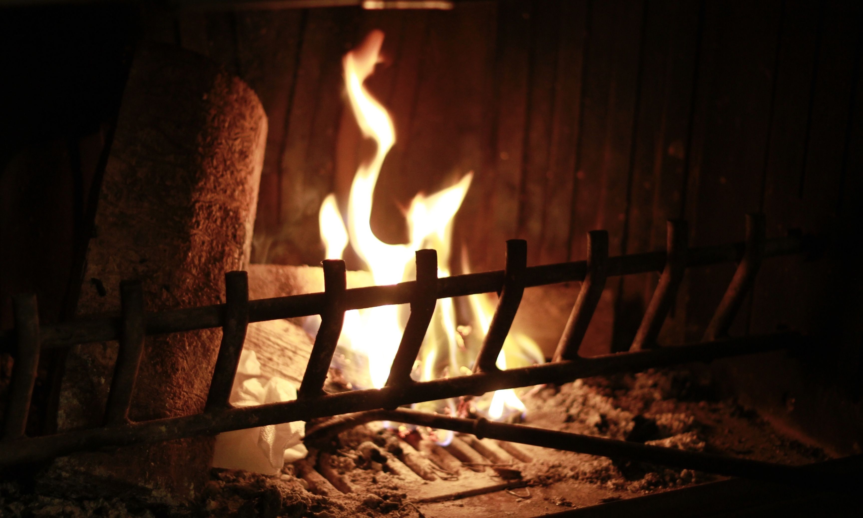 A close-up of a wooden fence in front of a fireplace with visible flames.