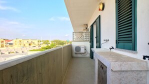 A balcony with a view of buildings, a sink, and a window with shutters. - Bilocale Rosalba (Gallipoli)