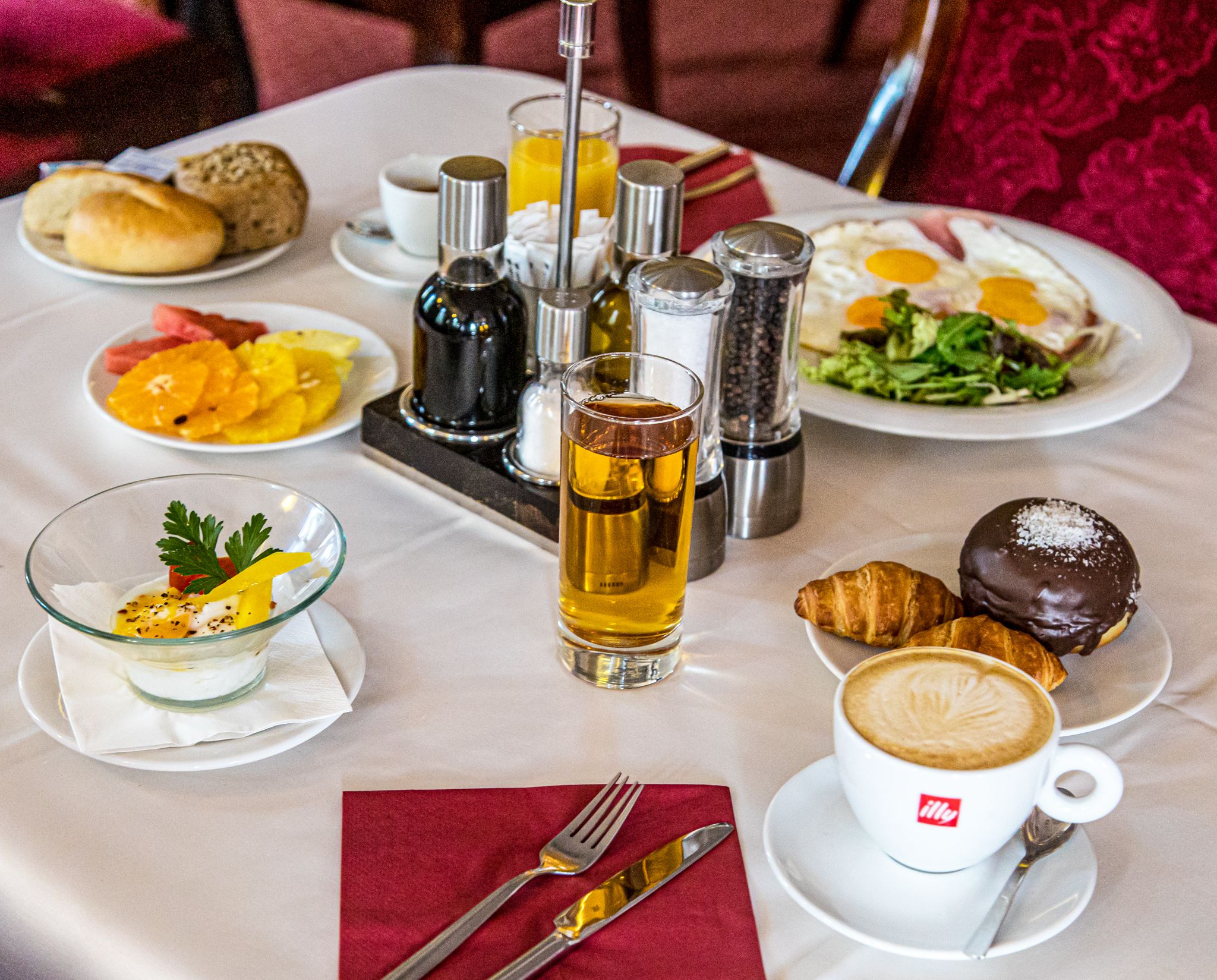 A breakfast setting with a variety of dishes including eggs, croissants, and a coffee cup.