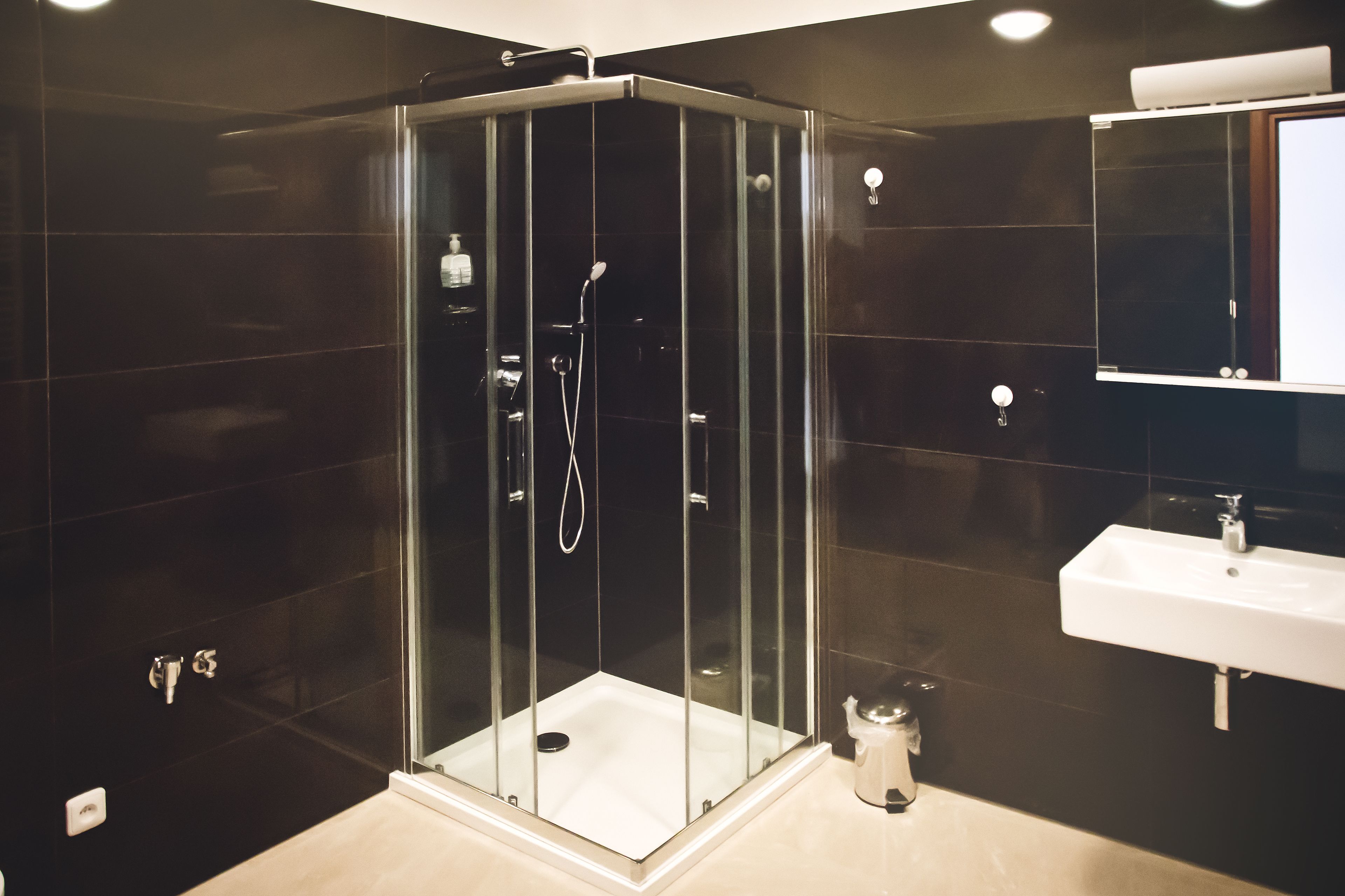 Une salle de bain moderne avec une douche à parois de verre, un lavabo blanc et un miroir au-dessus du lavabo.