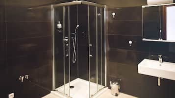 Une salle de bain moderne avec une douche à parois de verre, un lavabo blanc et un miroir au-dessus du lavabo.