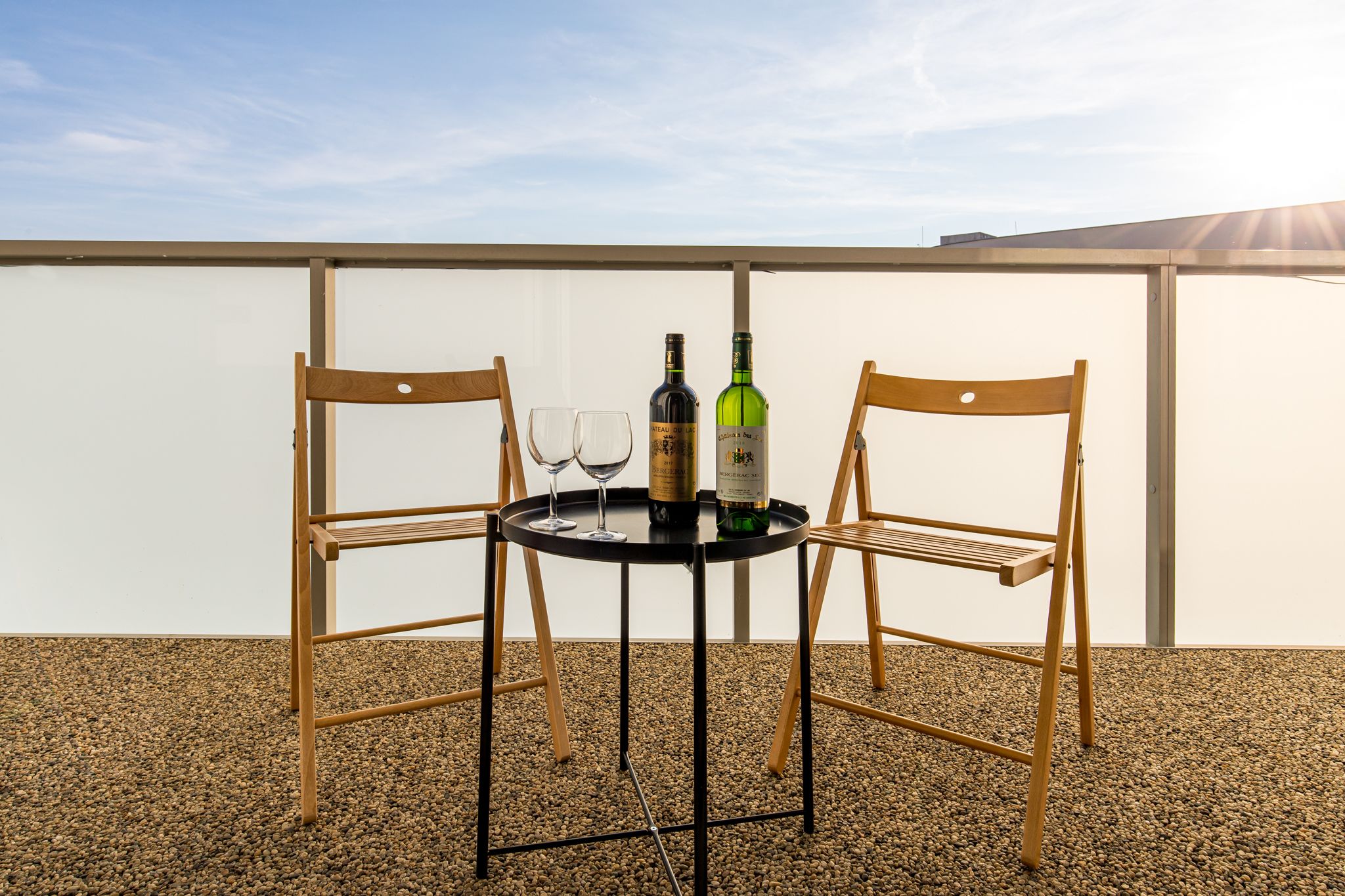 Ein Tisch mit zwei Stühlen und zwei Weingläsern, mit Weinflaschen darauf.