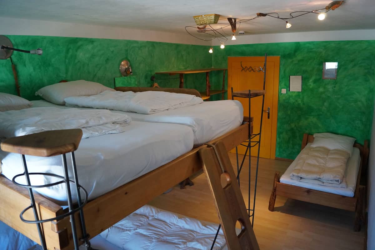 Una habitación con dos literas, un escritorio de madera, una silla y una pared verde.