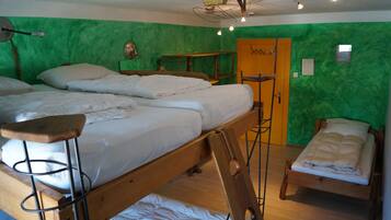Una habitación con dos literas, un escritorio de madera, una silla y una pared verde.