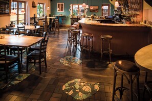 A restaurant with wooden tables and chairs, a bar area, and a mosaic floor design. - Schiff Bihlerdorf- Hostel (Blaichach)