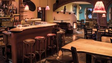 A bar area with stools, a bar counter, and hanging pendant lights.