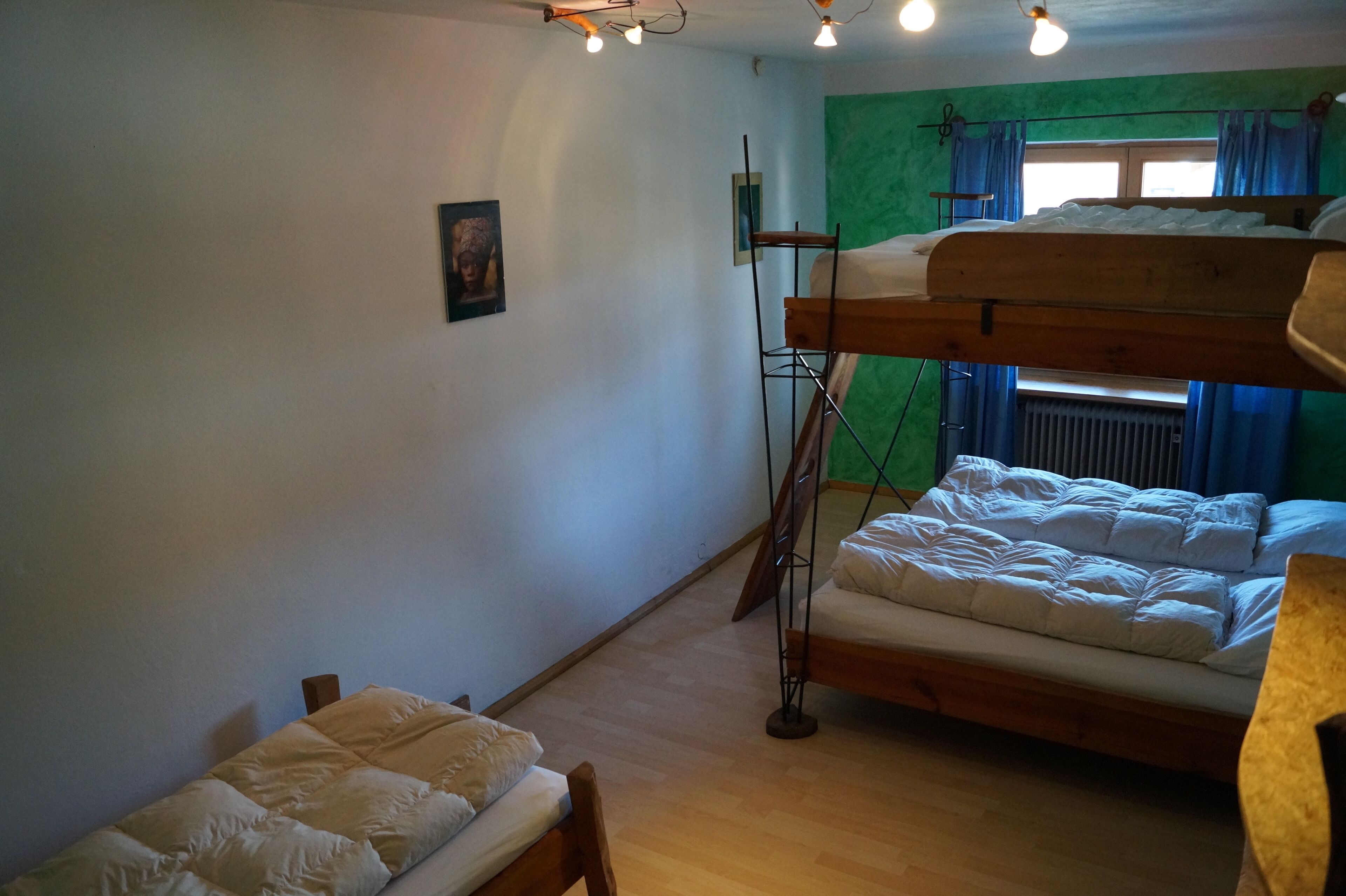 Et værelse med køjesenge, en radiator, et vindue med gardiner og en grøn væg.