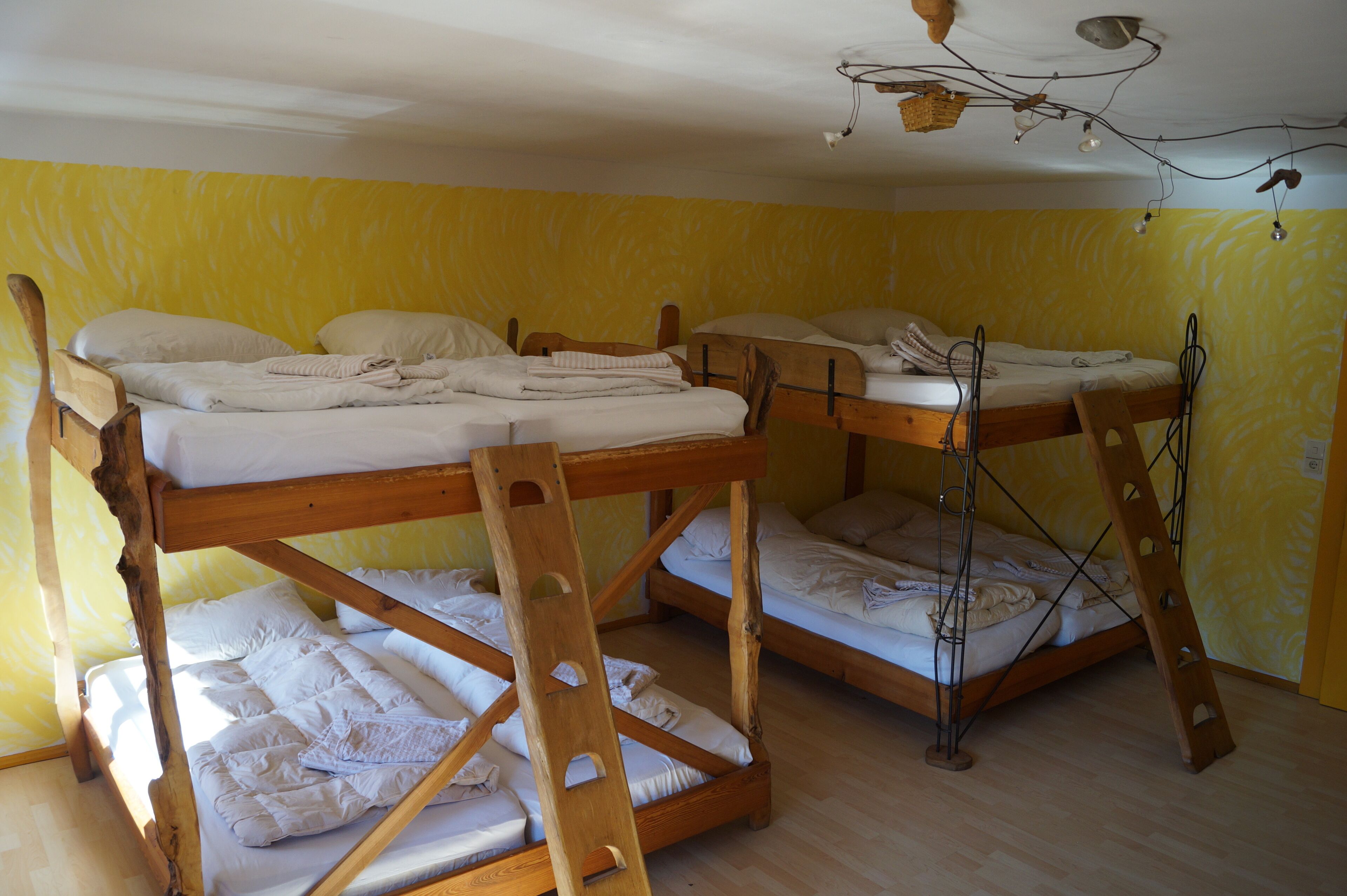 Quarto com beliches, estrutura de madeira e parede amarela.