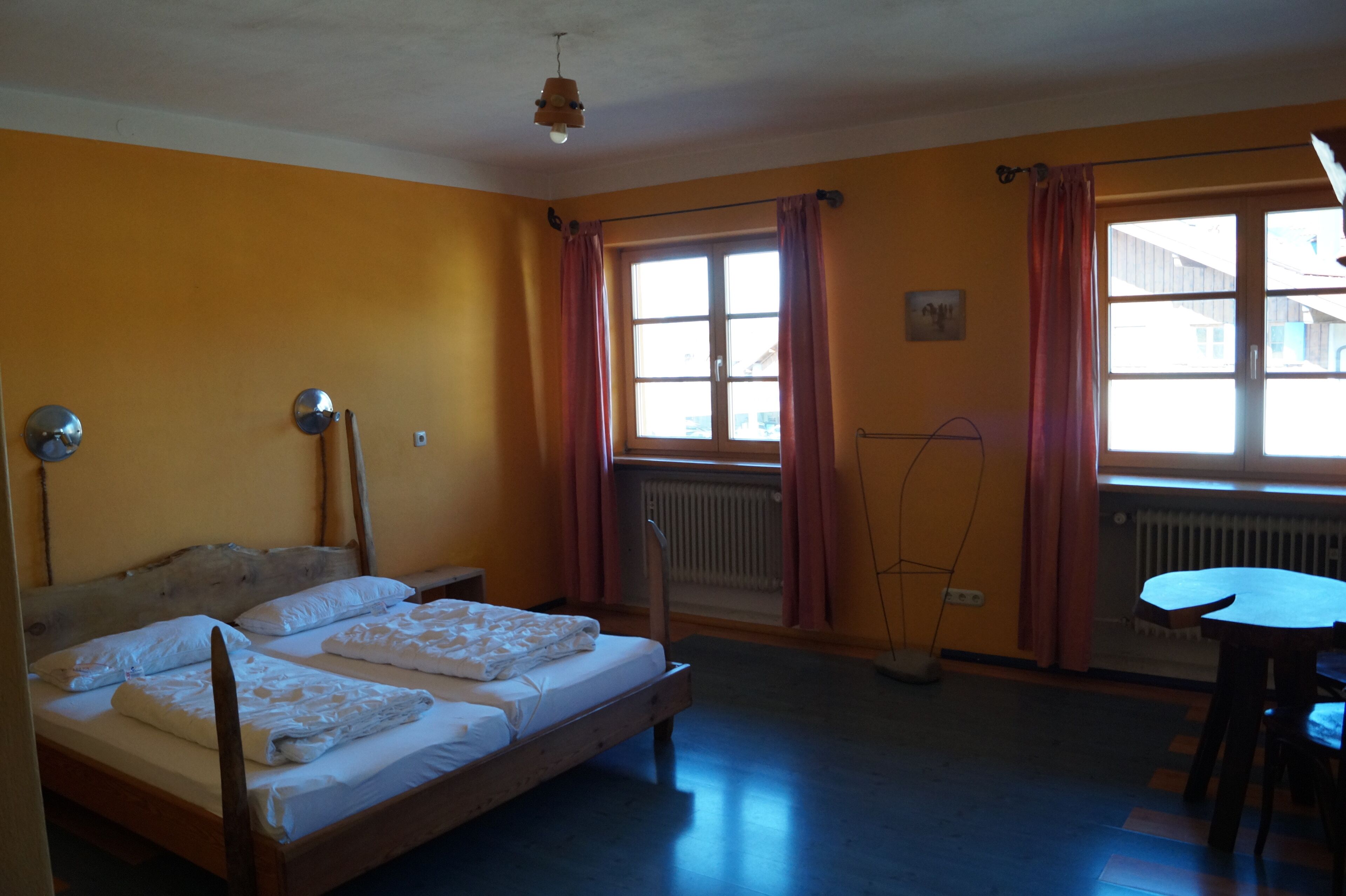 A room with a bed, a table, and a window with curtains.