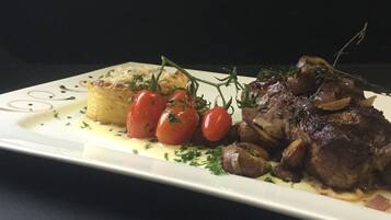 A plate with a steak, cherry tomatoes, and a side of potatoes.