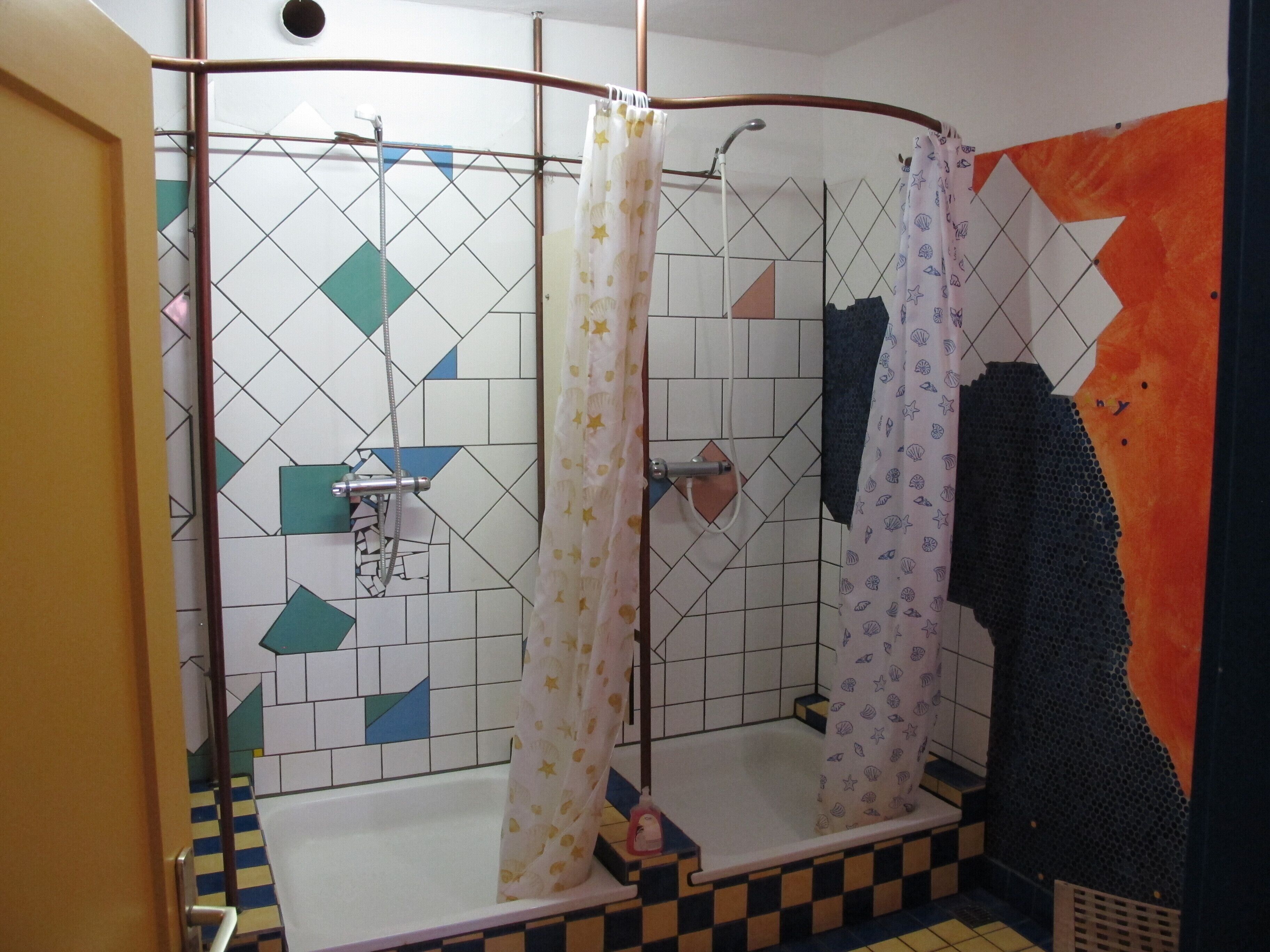 A shower area with a tiled wall, a shower curtain, and a bathtub.