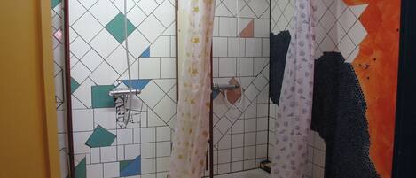 A shower area with a tiled wall, a shower curtain, and a bathtub.