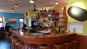 Una zona de bar con taburetes, estanterías llenas de botellas y un menú en una pizarra.