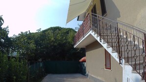A building with a staircase, a covered area, and a paved pathway.