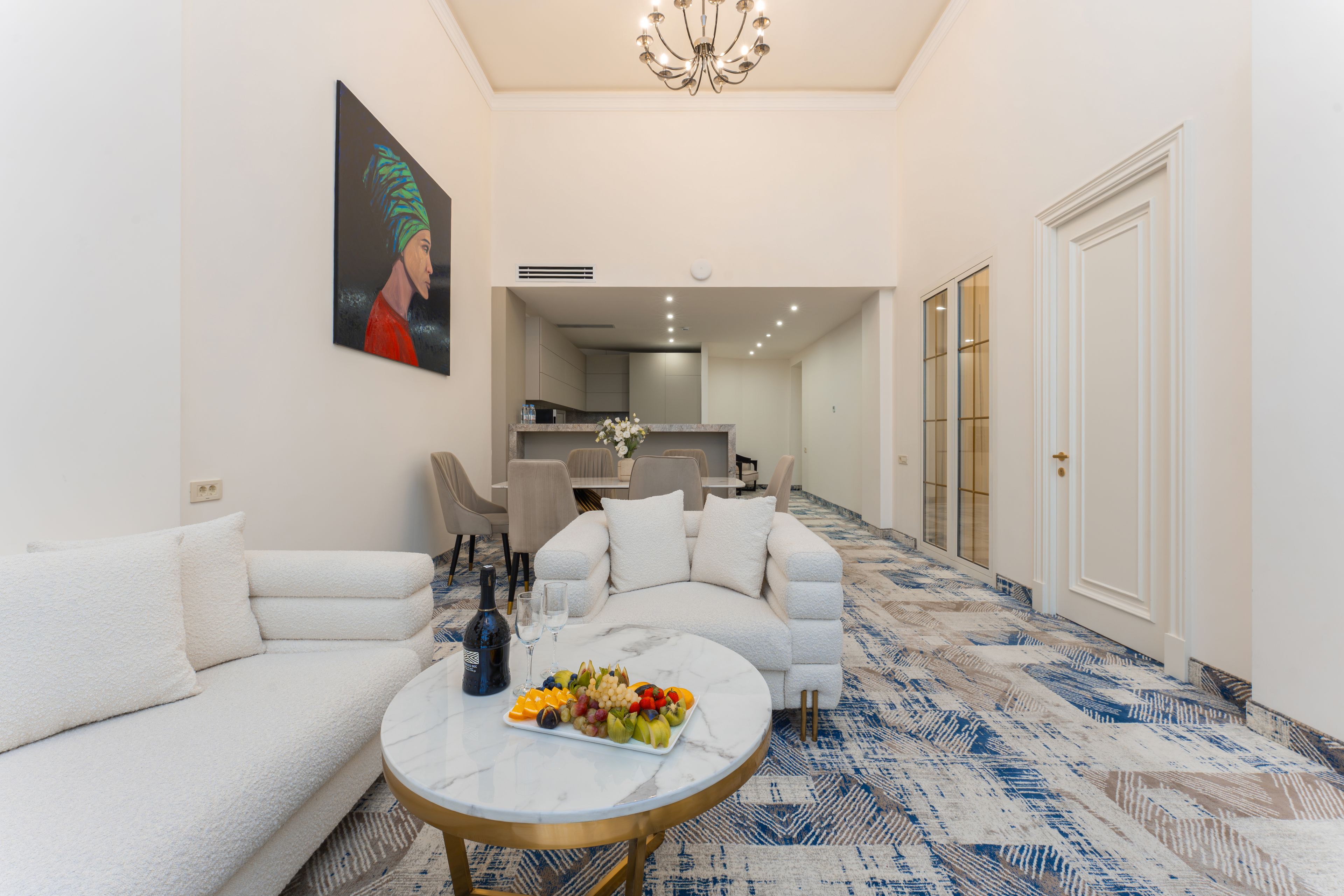A modern living room with a sofa, a coffee table with fruit, and a painting on the wall.