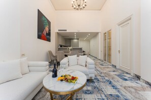 Una sala de estar moderna con un sofá, una mesa de centro con fruta y un cuadro en la pared.