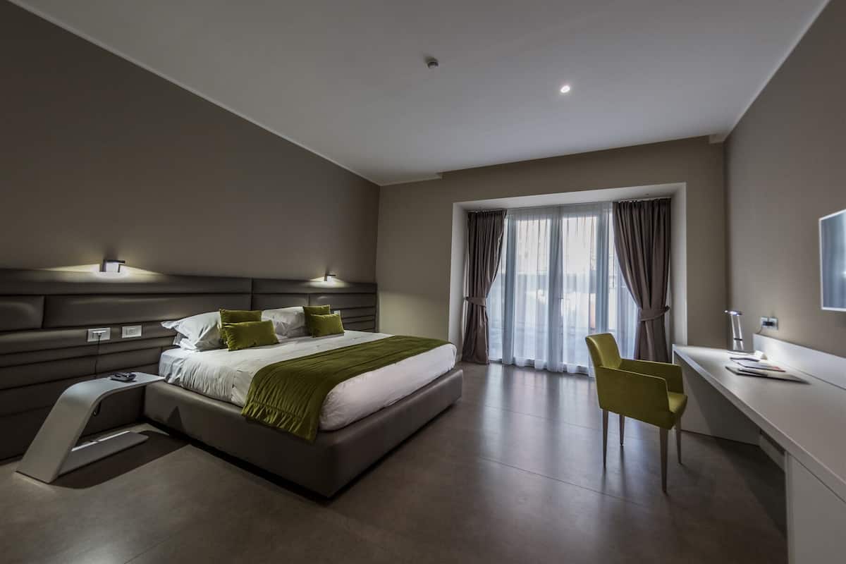 Une chambre moderne avec un lit, une table de chevet, une chaise, un bureau et une fenêtre avec des rideaux.