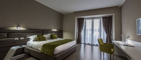 A modern bedroom with a bed, bedside table, chair, desk, and window with curtains.