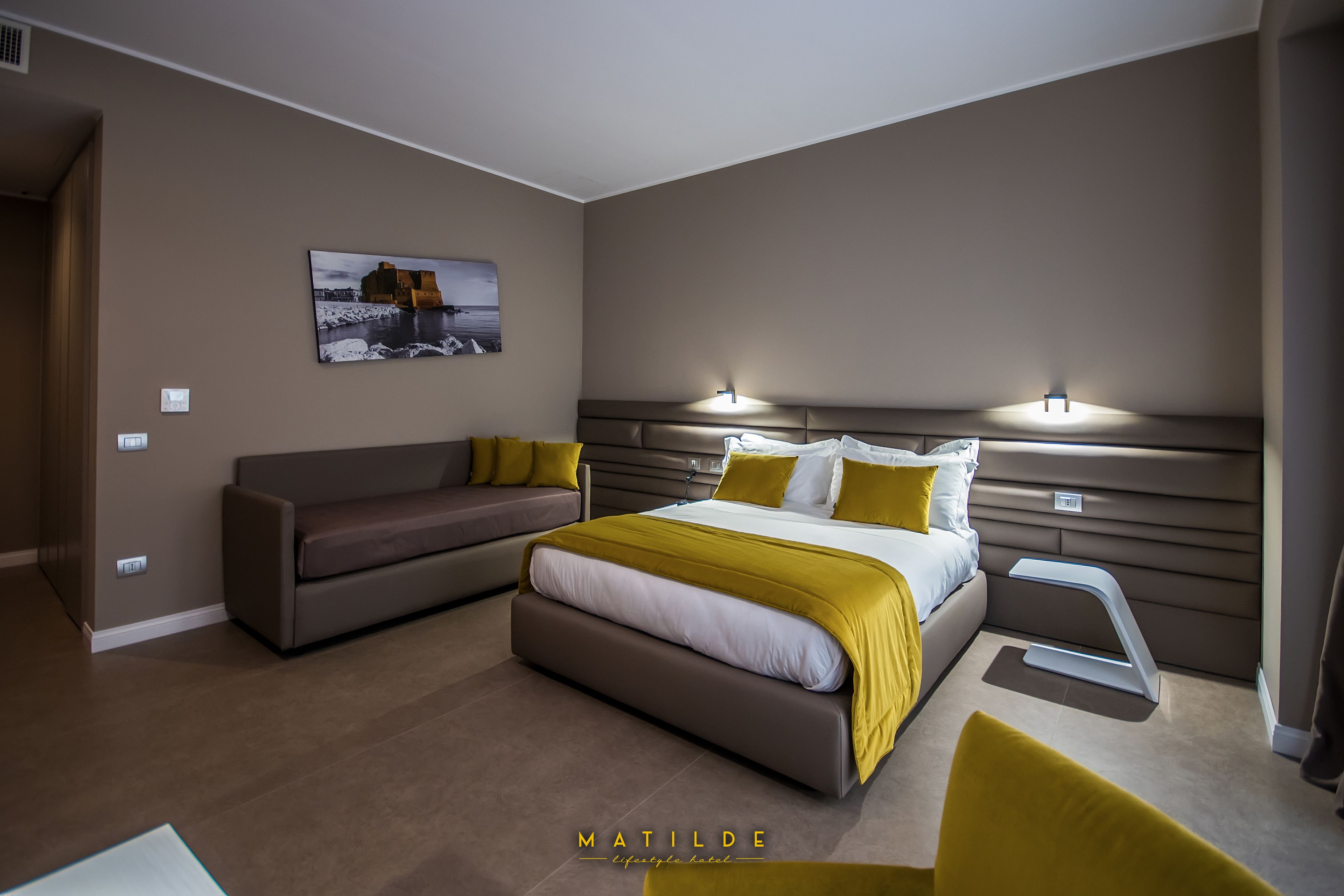Een moderne slaapkamer met een groot bed, een bank en een nachtkastje.