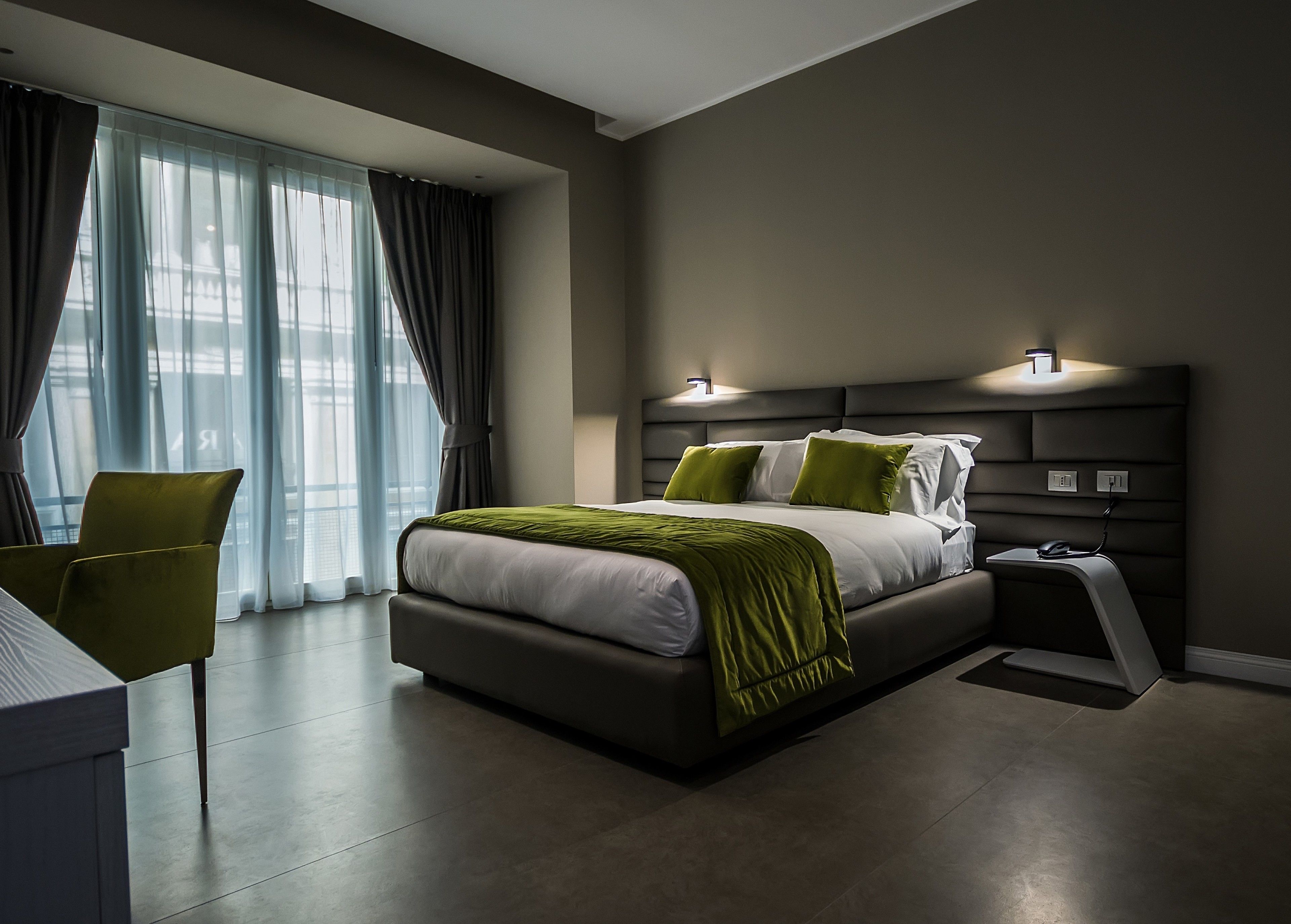 A modern hotel room with a large bed, a desk, and a chair.