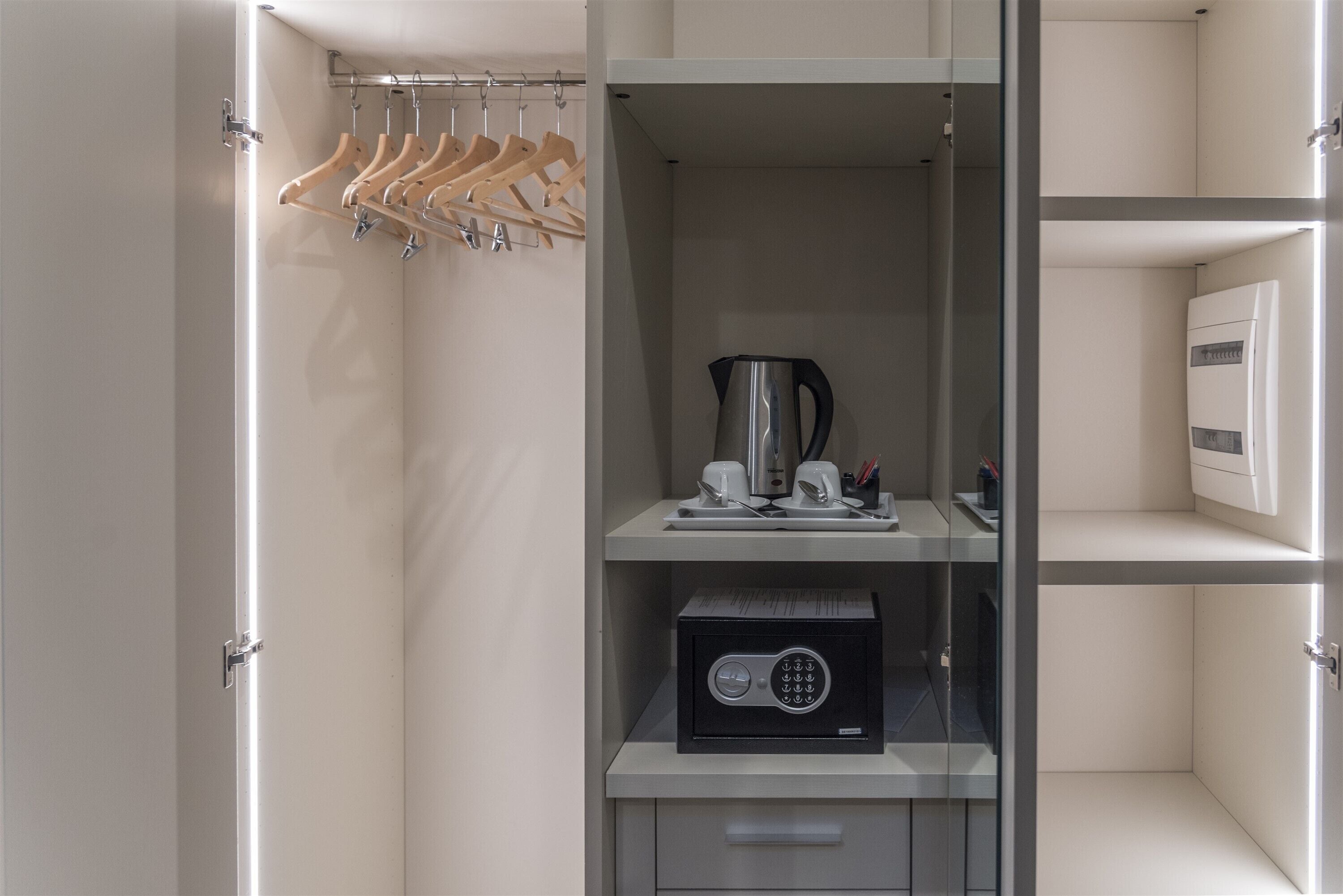 Un armadio moderno e ben organizzato con spazio per appendere, una macchina del caffè e una cassaforte.