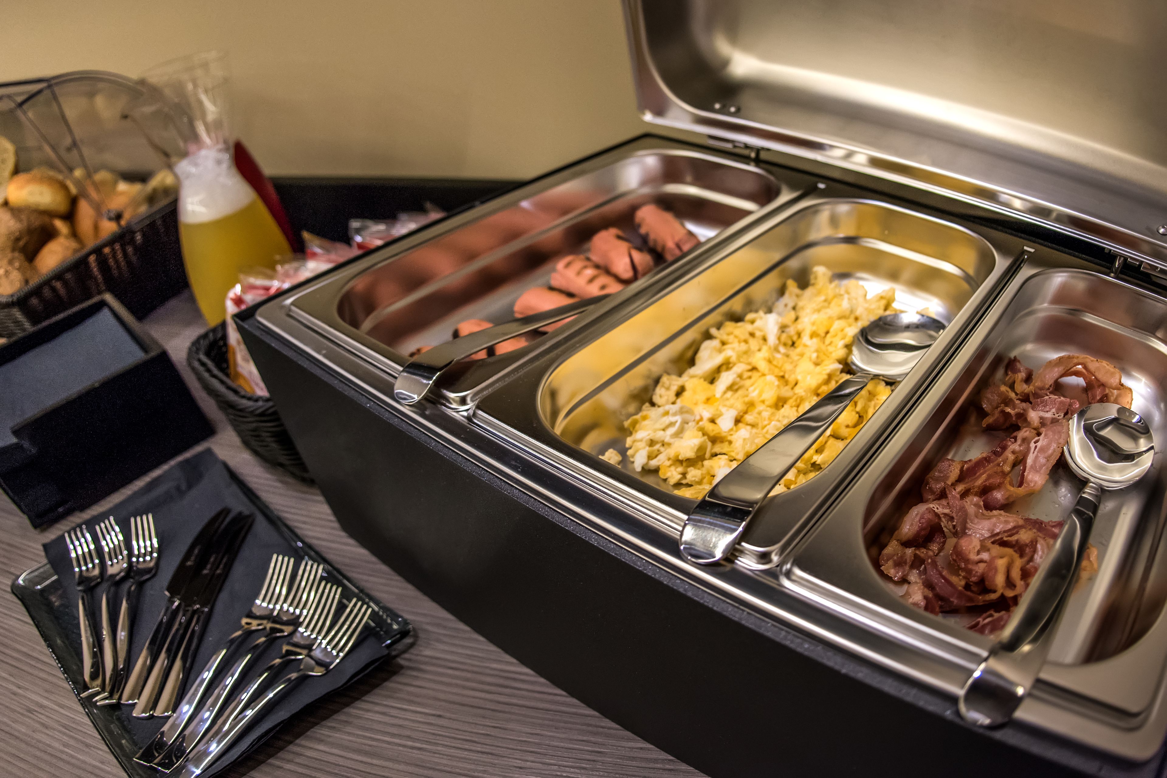 A buffet with various food options including scrambled eggs, bacon, and other dishes.