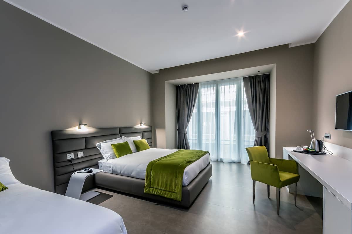 Une chambre d’hôtel moderne, dotée d’un grand lit, de tables de chevet, d’un bureau et d’une chaise.