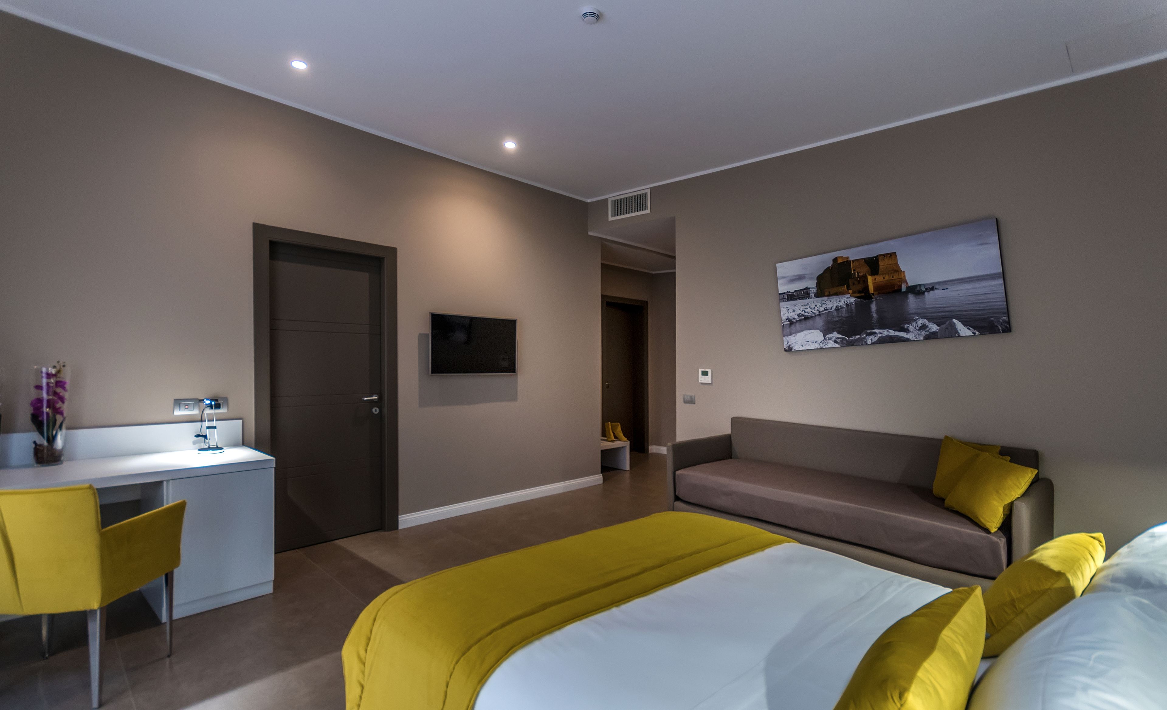 Una habitación de hotel moderna con cama, sofá, escritorio y silla.