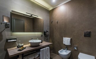 Een moderne badkamer met een grote spiegel, een wastafel, een hygiëneschuimer en een handdoekrek.