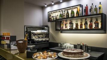 A bar area with a variety of liquor bottles, a coffee machine, and a selection of pastries and desserts.