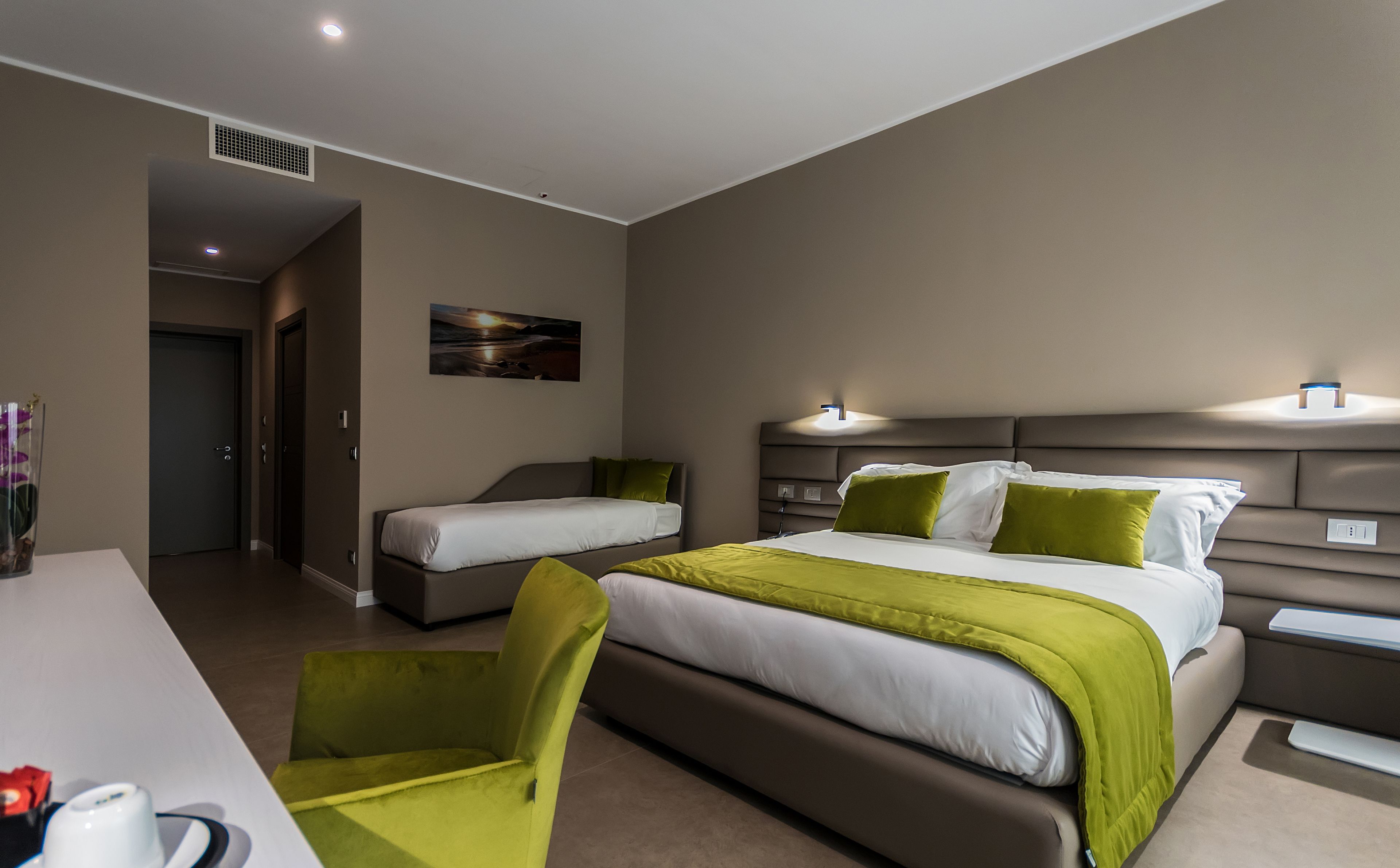 Camera d'albergo con due letti singoli, una scrivania, una sedia e un quadro appeso al muro.