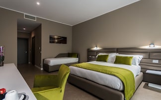 Camera d'albergo con due letti singoli, una scrivania, una sedia e un quadro appeso al muro.