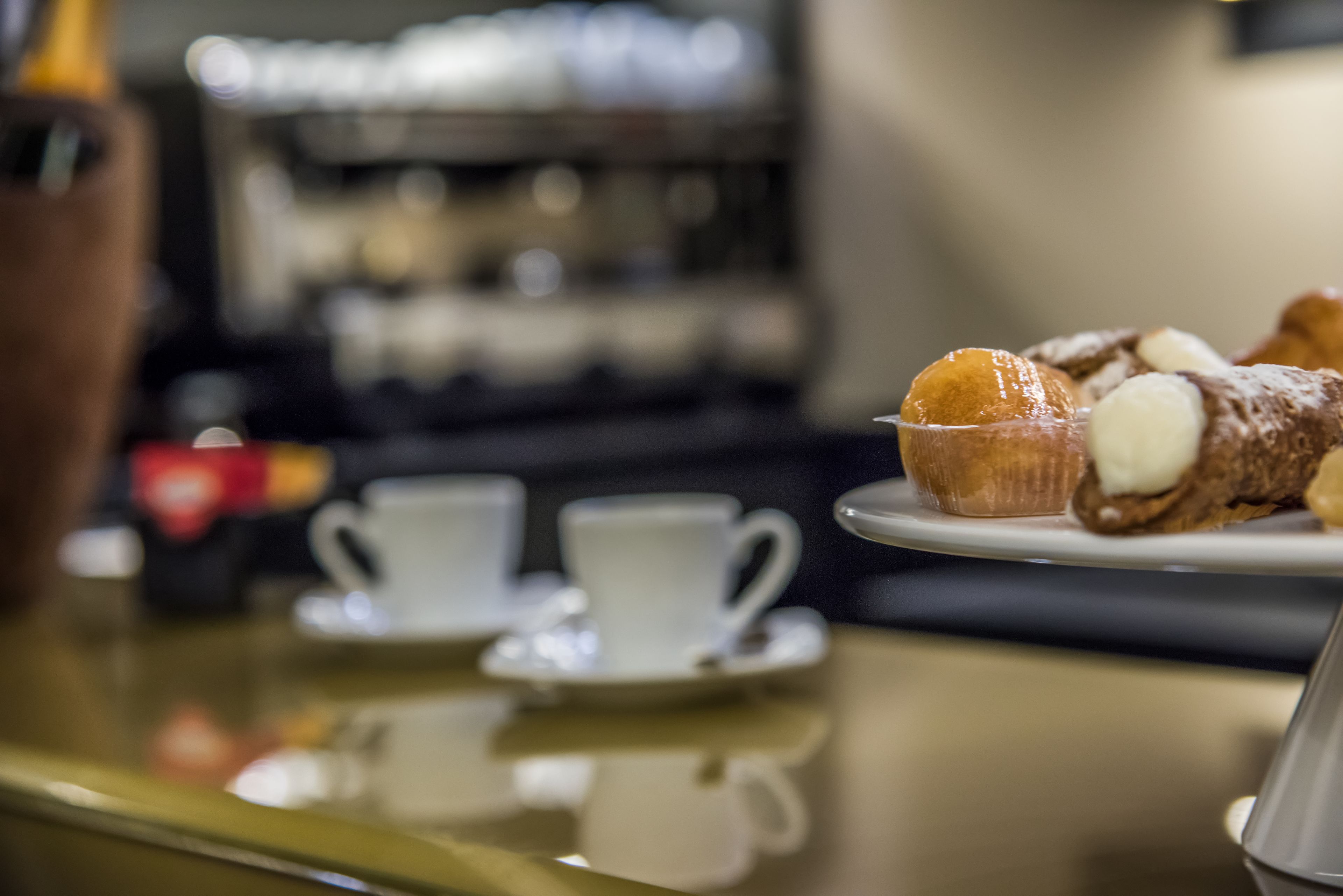 A table with two white cups and a plate of pastries.