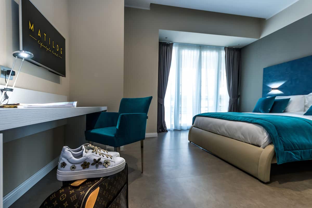 Une chambre d’hôtel moderne, équipée d’un lit, d’un bureau et d’une chaise.