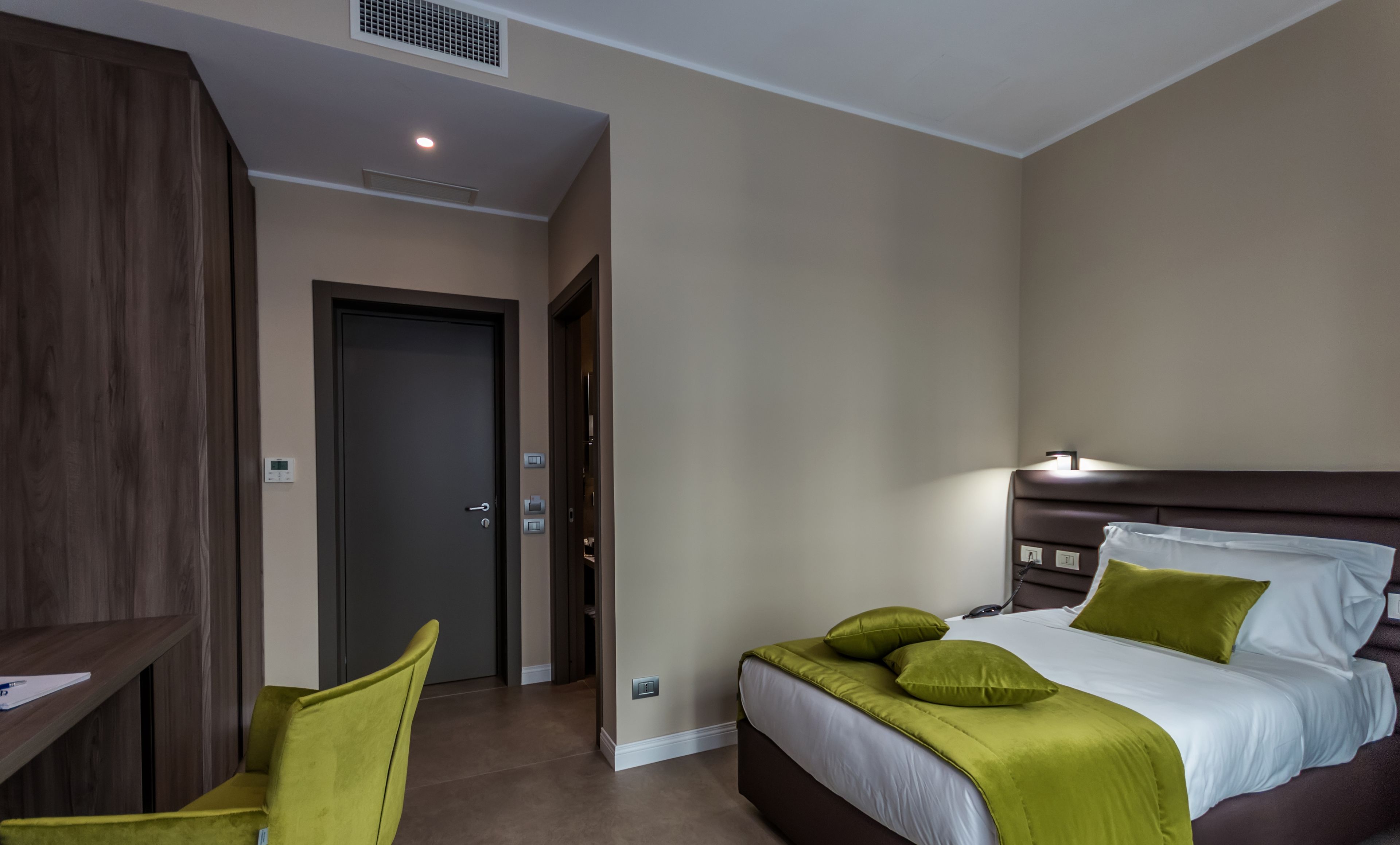 A hotel room with a bed, a desk, and a chair.