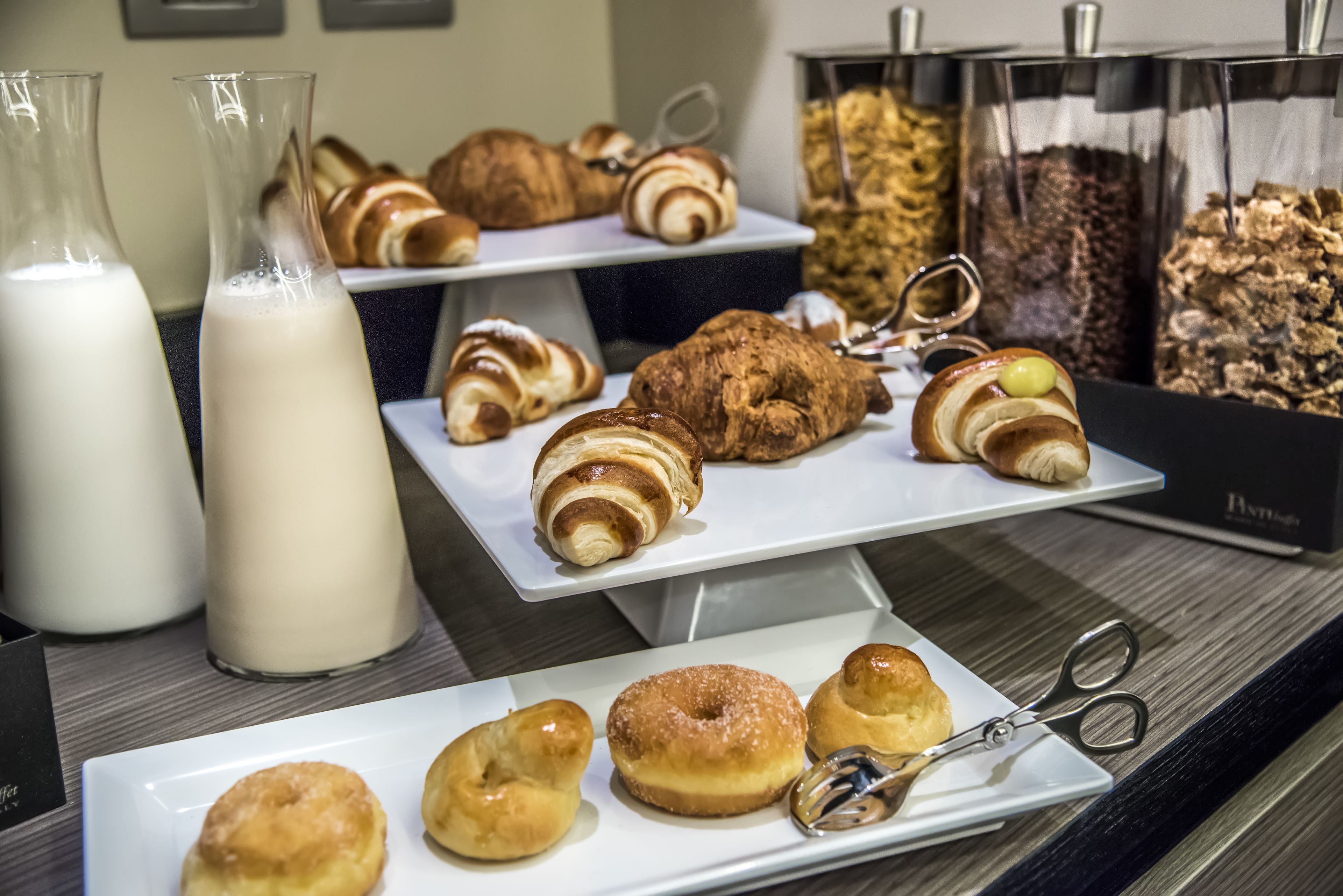 Ein Frühstücksbuffet mit Gebäck, Milch und einer Schere auf einem Tablett.