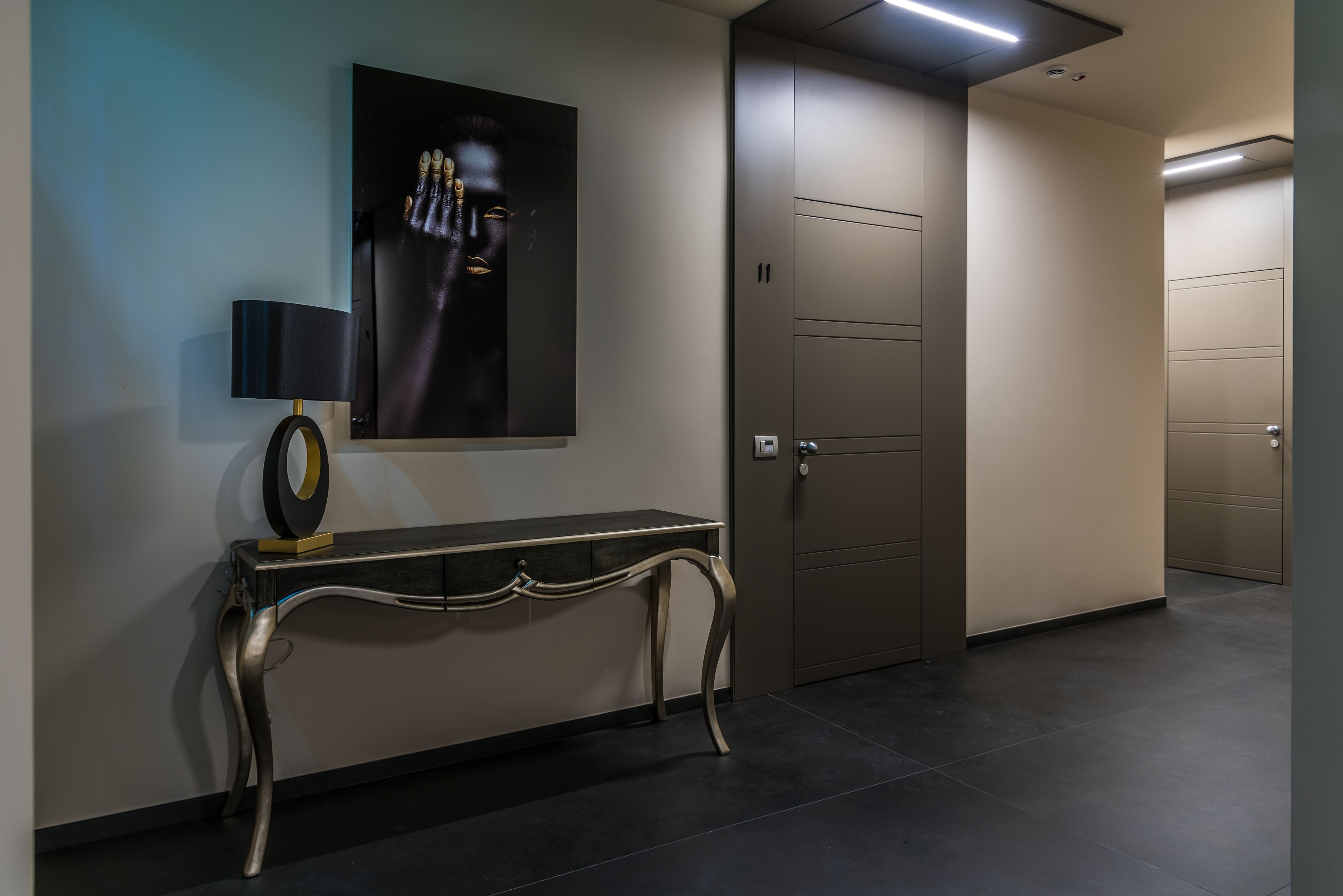 A modern hallway with a console table, a framed artwork, and a door.