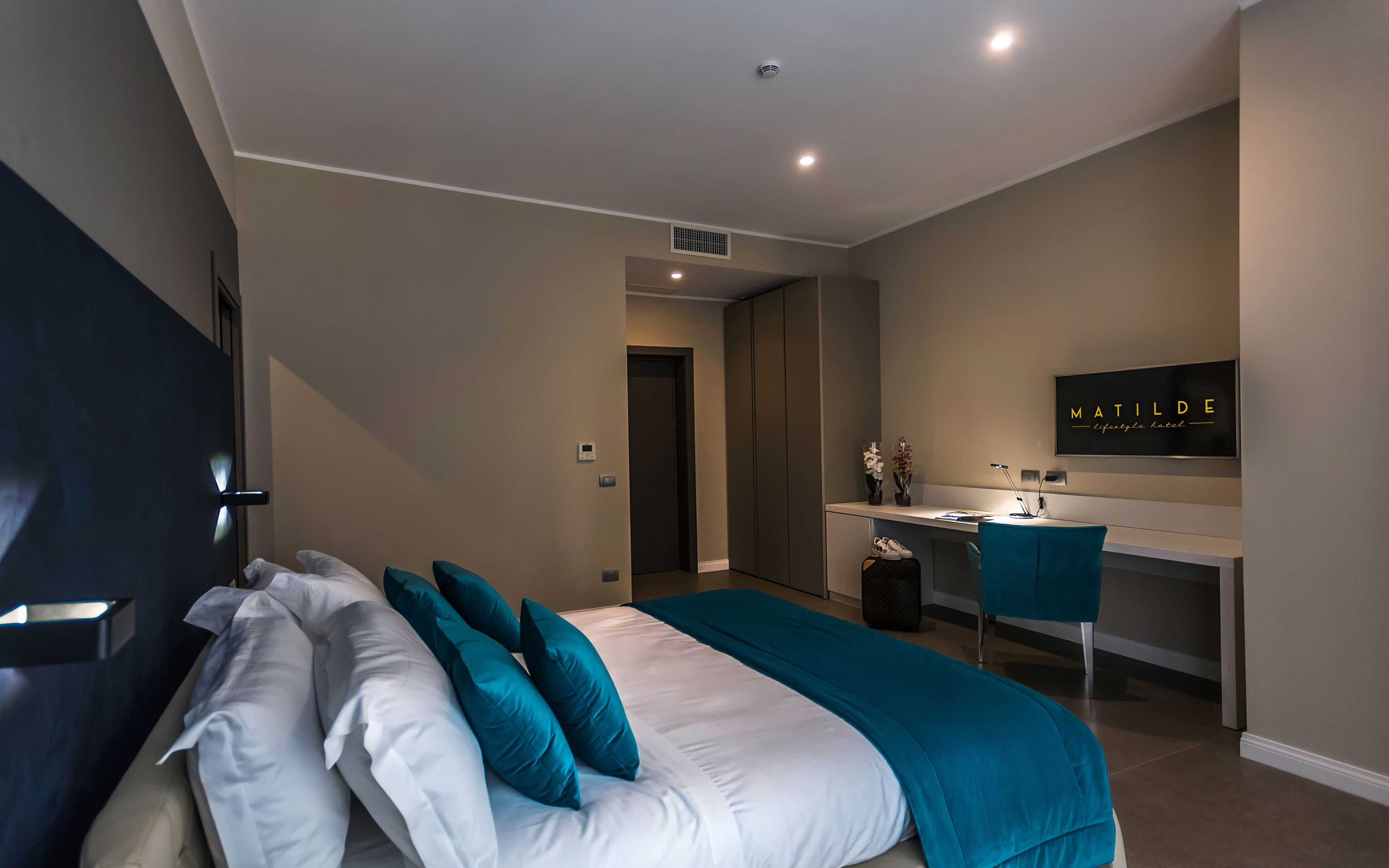 Een moderne hotelkamer met een bed, een bureau en een stoel.