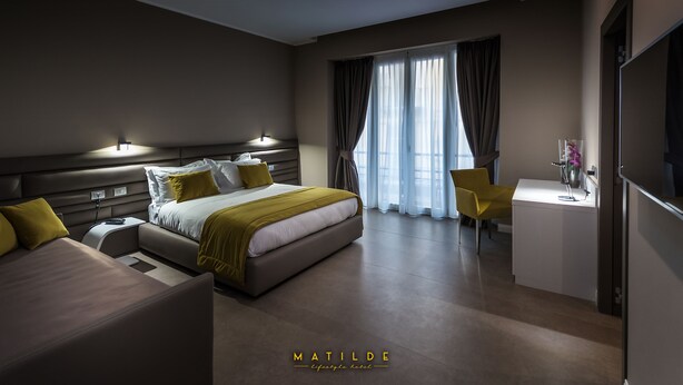 A modern hotel room with a bed, bedside tables, a desk, and a large window with curtains. - Hotel Matilde - Lifestyle Hotel (Naples)